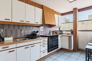 Une cuisine moderne avec des armoires blanches, des plans de travail en bois, un four encastré et un lave-vaisselle.