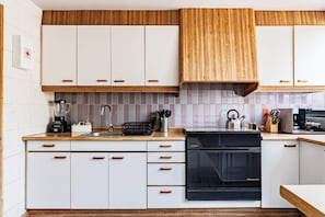 A modern kitchen with white cabinets, a black dishwasher, and a wooden countertop. - 3BR Near Reforma & Mexico City Historic Center (Mexico City)