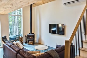 Una sala moderna con un sofá modular, una mesa redonda de centro, una chimenea y un televisor de pared.