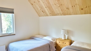 A bedroom with two beds, a nightstand with a lamp, and a window with blinds. - Nordic Forest Chalet near Mont Tremblant | 32+ Days | Pet Friendly! (Lac-Supérieur)