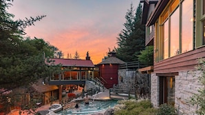 A modern house with a stone exterior, a swimming pool, and a waterfall feature. - Nordic Forest Chalet near Mont Tremblant | 32+ Days | Pet Friendly! (Lac-Supérieur)