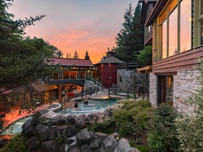 Una casa moderna con fachada de piedra, piscina y una cascada.