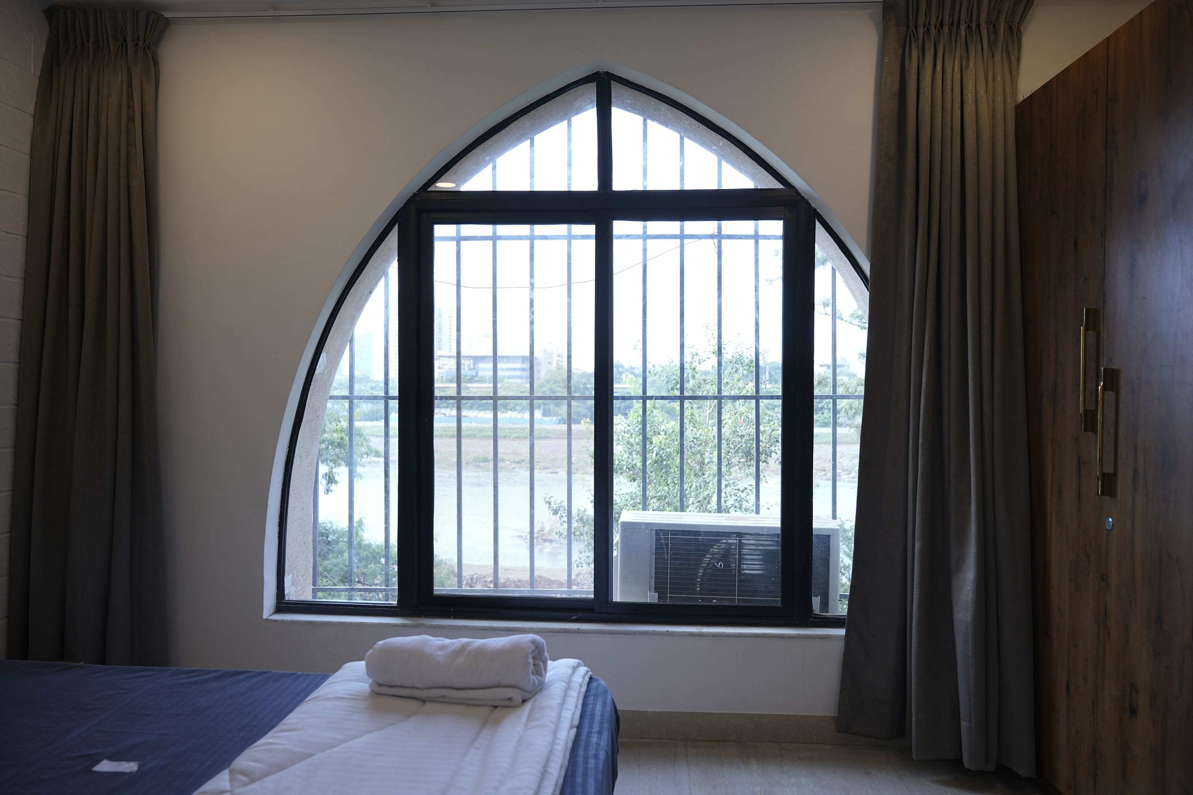 Una camera da letto con un'ampia finestra ad arco, un letto e tende.