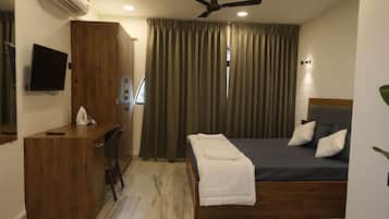 Ein Hotelzimmer mit Bett, Schreibtisch, Fernseher und Deckenventilator.