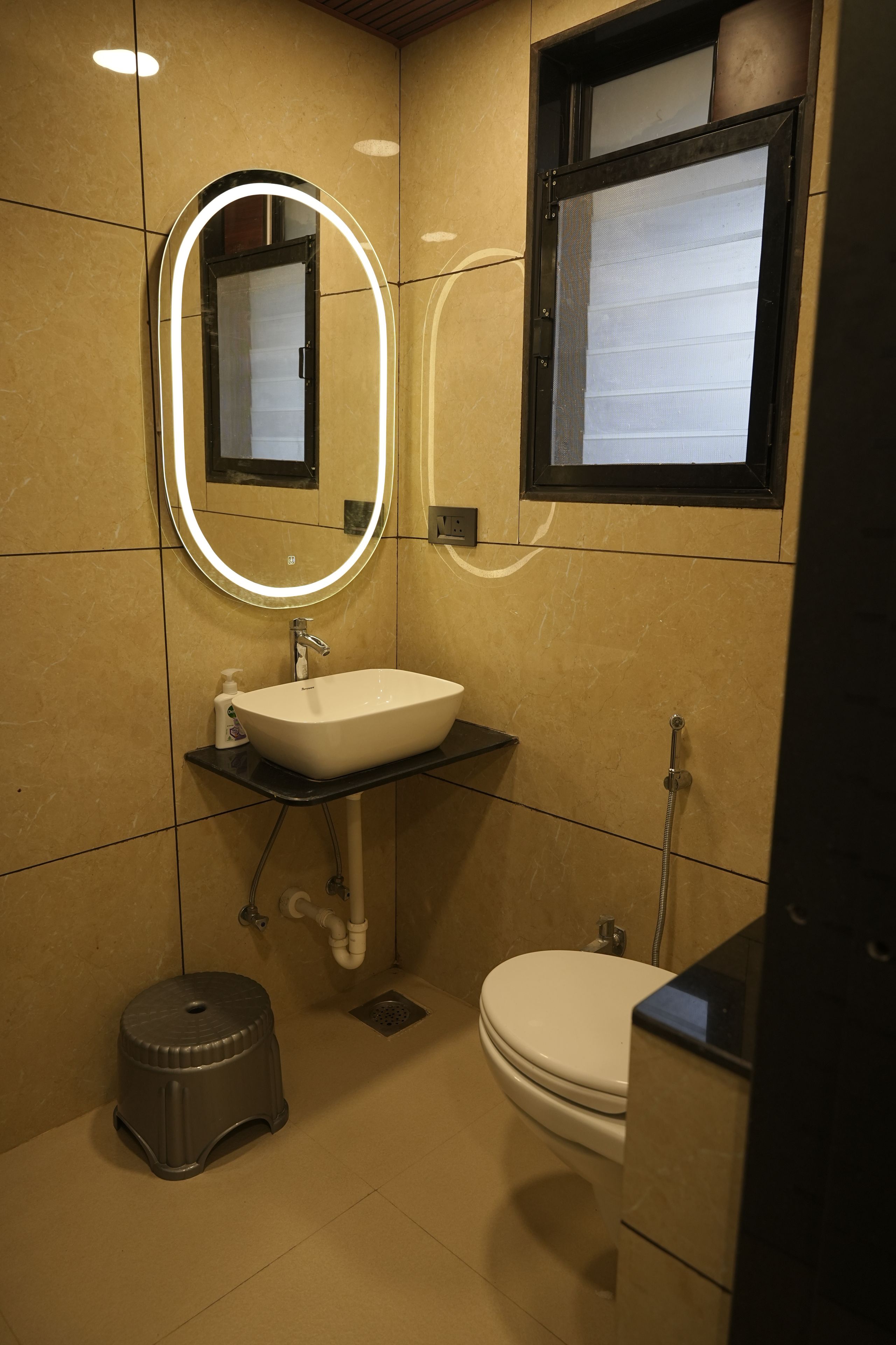 Een badkamer met een witte wasbak, een spiegel met verlichting, een toilet en een douche.