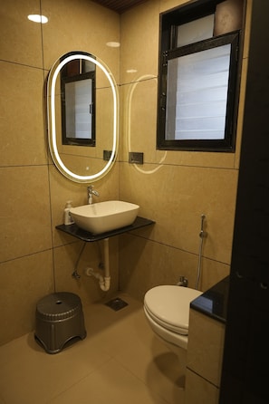 Een badkamer met een witte wasbak, een spiegel met verlichting, een toilet en een douche.