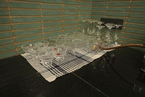 A table with various glassware items, including wine glasses and bowls, arranged on a checkered cloth.