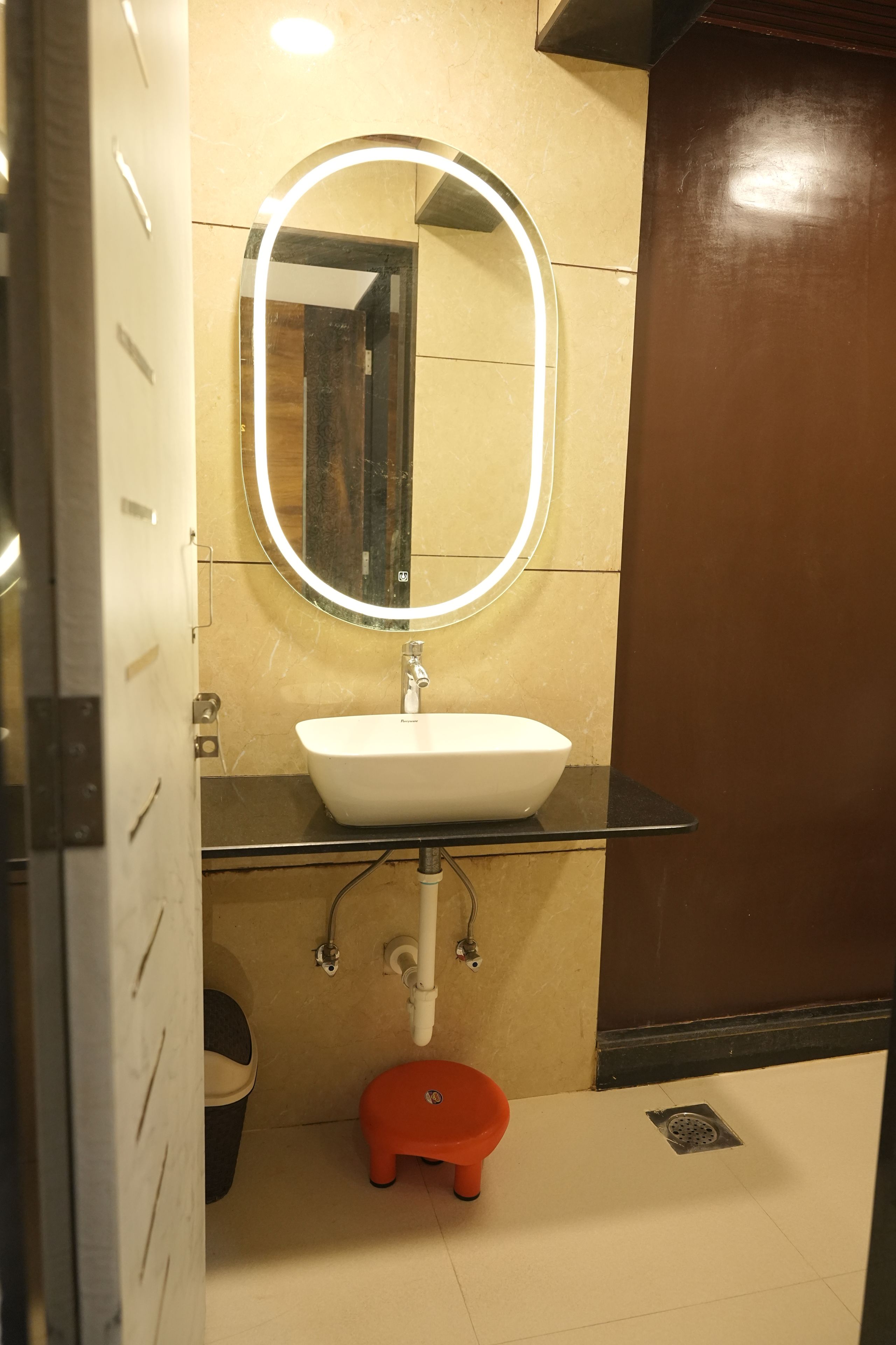 A bathroom with a white sink, a mirror, and a red stool.