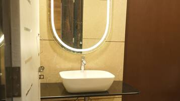 A bathroom with a white sink, a mirror, and a red stool.