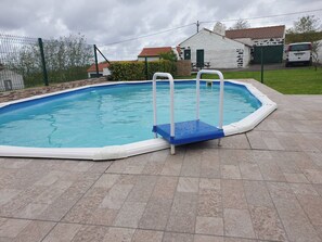 An outdoor swimming pool with a blue and white border, surrounded by a fence, and a paved area with a bench. - Rocha Mar House | Country House with Private Pool and Ocean View (Nordestinho)