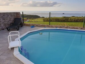A swimming pool with a view of the sea, surrounded by a fence and a stone wall. - Rocha Mar House | Country House with Private Pool and Ocean View (Nordestinho)