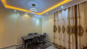 A conference room with a round table, chairs, and a patterned curtain.