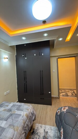 A bedroom with a large wardrobe, two beds, and a ceiling with recessed lighting.