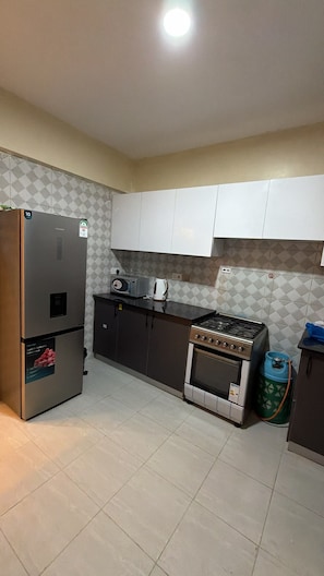 Una cocina con refrigerador, estufa y armarios.