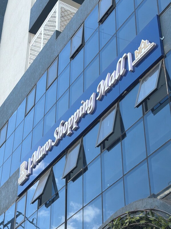 A building with a large glass facade and a sign that reads 'Plan Shopping Mall.'