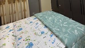 Un dormitorio con cama, cortinas, armario y lámpara de techo.