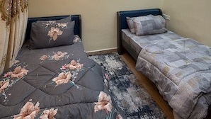 Un dormitorio con dos camas, una lámpara de techo y un aplique de pared.