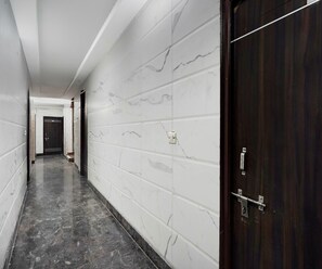 A corridor with white marble walls and a dark wooden door.