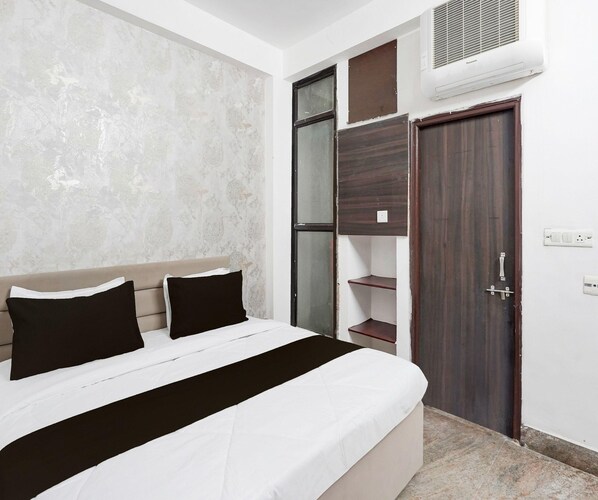 A bedroom with a bed, a wardrobe, and an air conditioning unit.