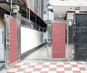 Una entrada tancada amb un sòl a escacs, reixes metàl·liques i una façana d'edifici amb una paret blanca i una columna de marbre negre.