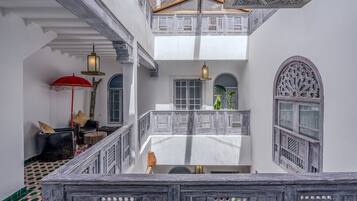 Un interior de varios niveles con balcón, paredes blancas y barandillas de madera tradicionales.