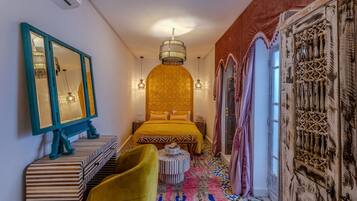 Una habitación con una cama, un espejo, una araña y una alfombra estampada.
