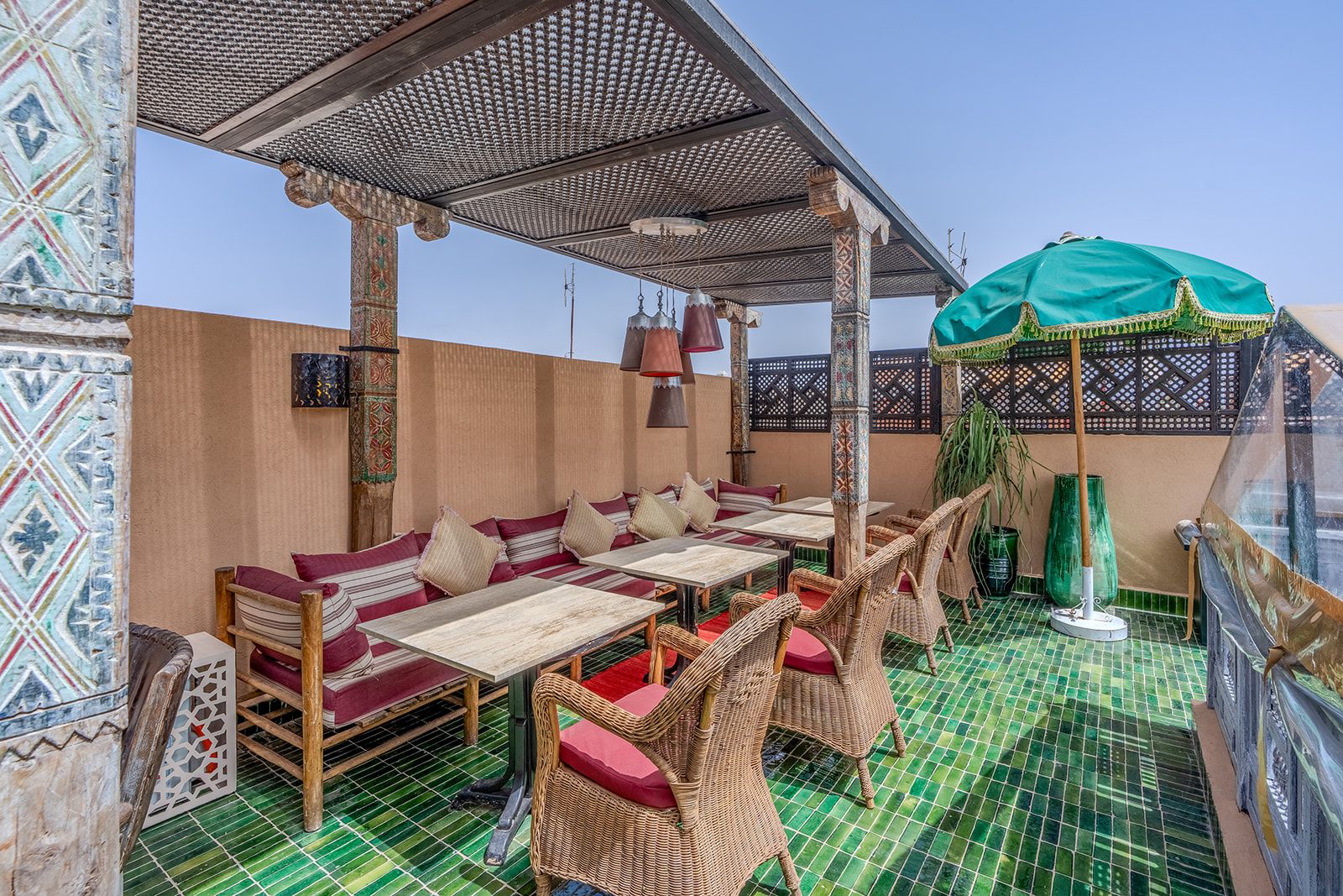 Un espace extérieur aménagé avec des meubles en osier et un parasol vert.