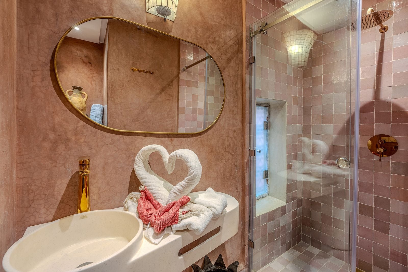 Un baño con una toalla con forma de corazón, un espejo grande y una zona de ducha.