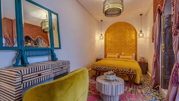 Una habitación con una cama, un espejo, un aparador de madera, un taburete redondo y una lámpara colgante.