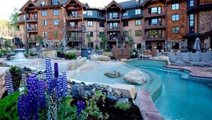 Un hotel su più piani con area piscina, posti a sedere all'aperto e una cascata.