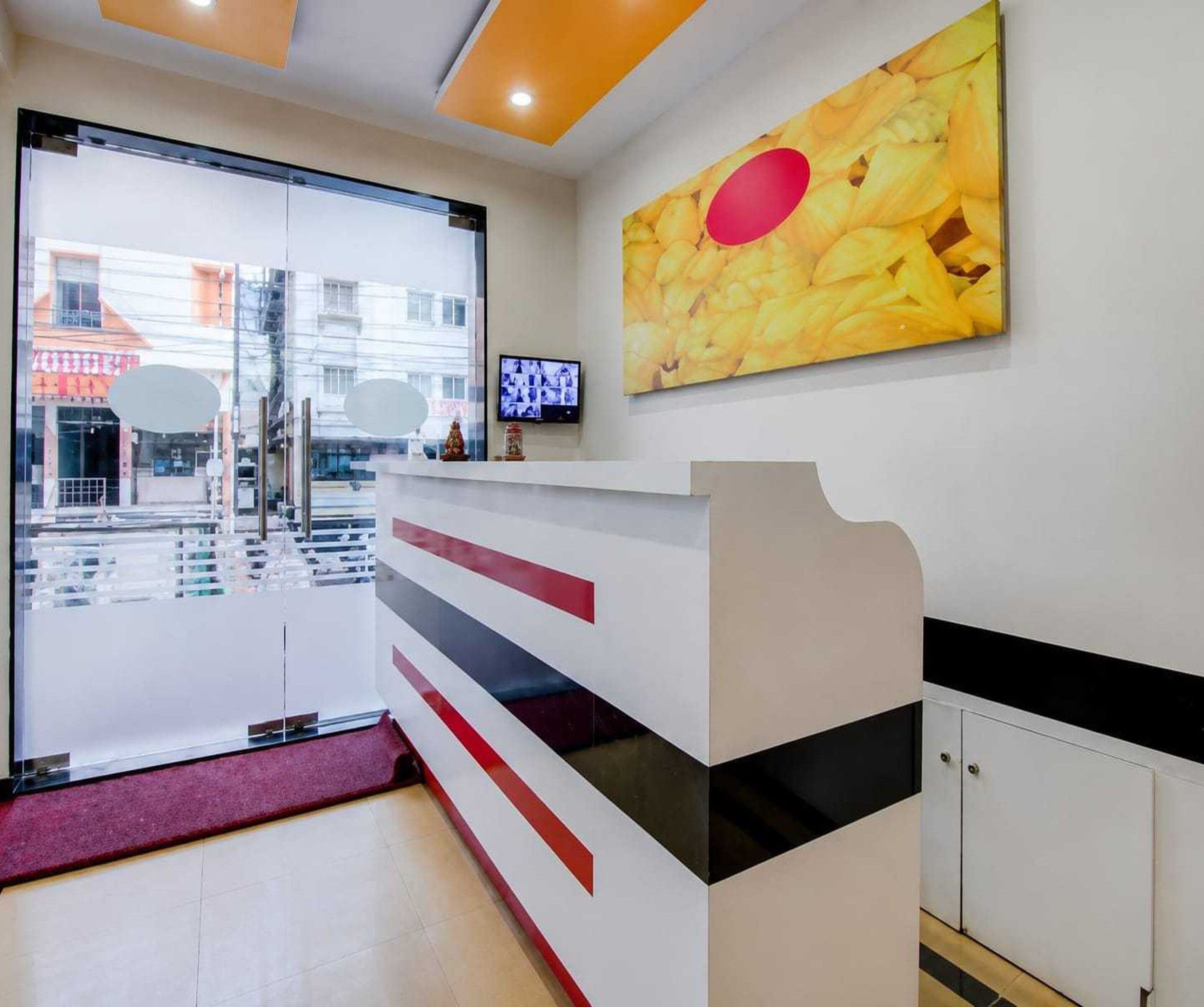 Un espace d’accueil doté d’une porte en verre, d’un téléviseur à écran plat et d’un tableau accroché au mur.