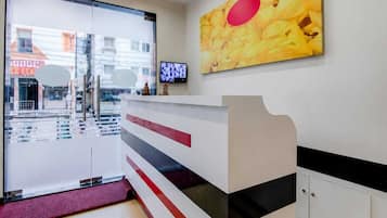 Un espace d’accueil doté d’une porte en verre, d’un téléviseur à écran plat et d’un tableau accroché au mur.