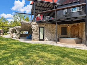 Un bâtiment moderne avec une façade en pierre, un jacuzzi et un espace extérieur aménagé avec des sièges.