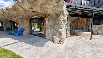 A building with a rock-like facade, a door labeled 'QUARTZ CAVE,' blue chairs outside, and a hot tub area.