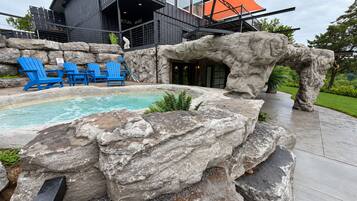 A modern building with a pool area featuring blue chairs and large rocks.