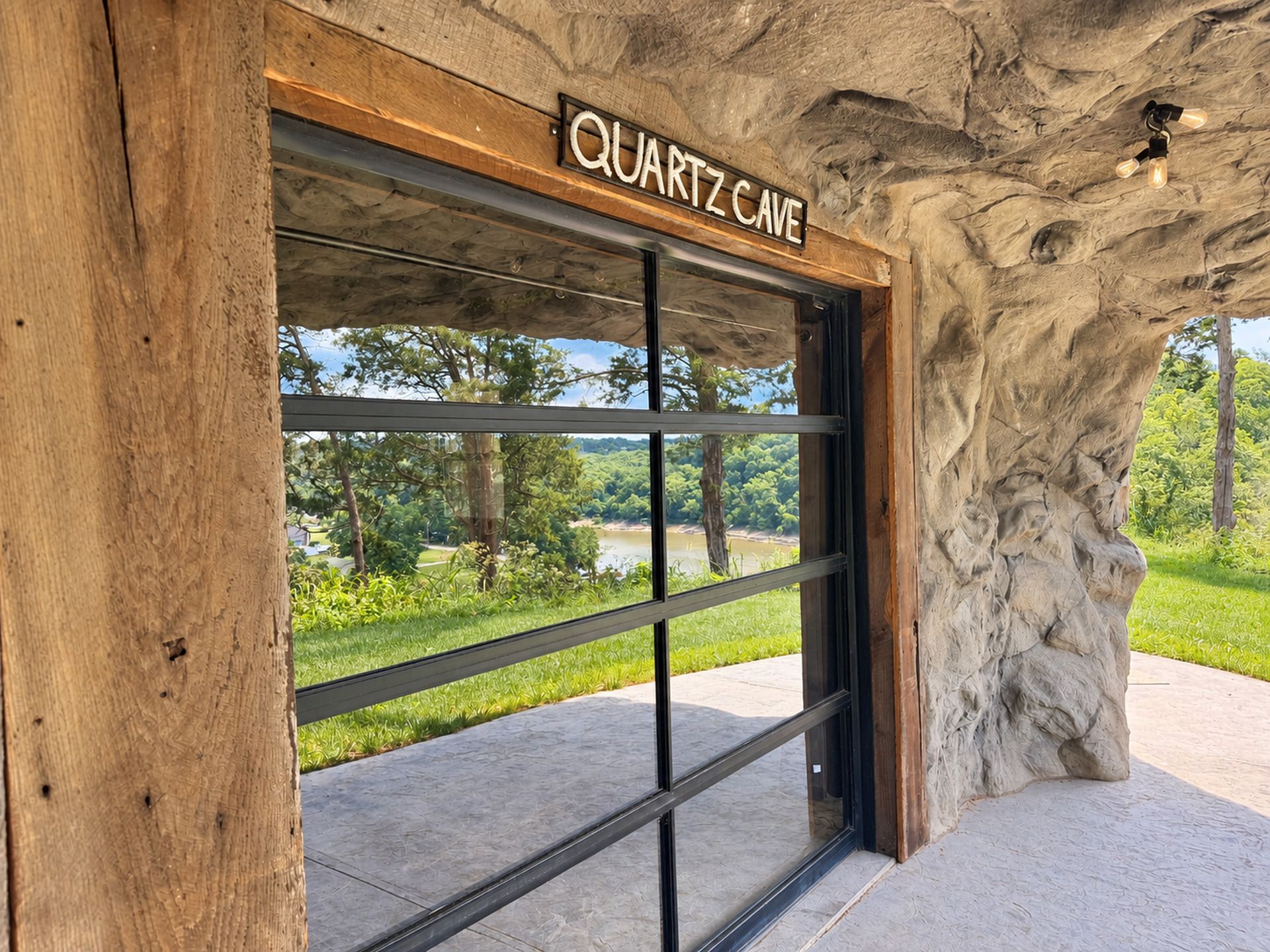 En byggnadsingång med en skylt som visar texten ”QUARTZ CAVE” och en utsikt över ett grönt landskap genom glasdörren.