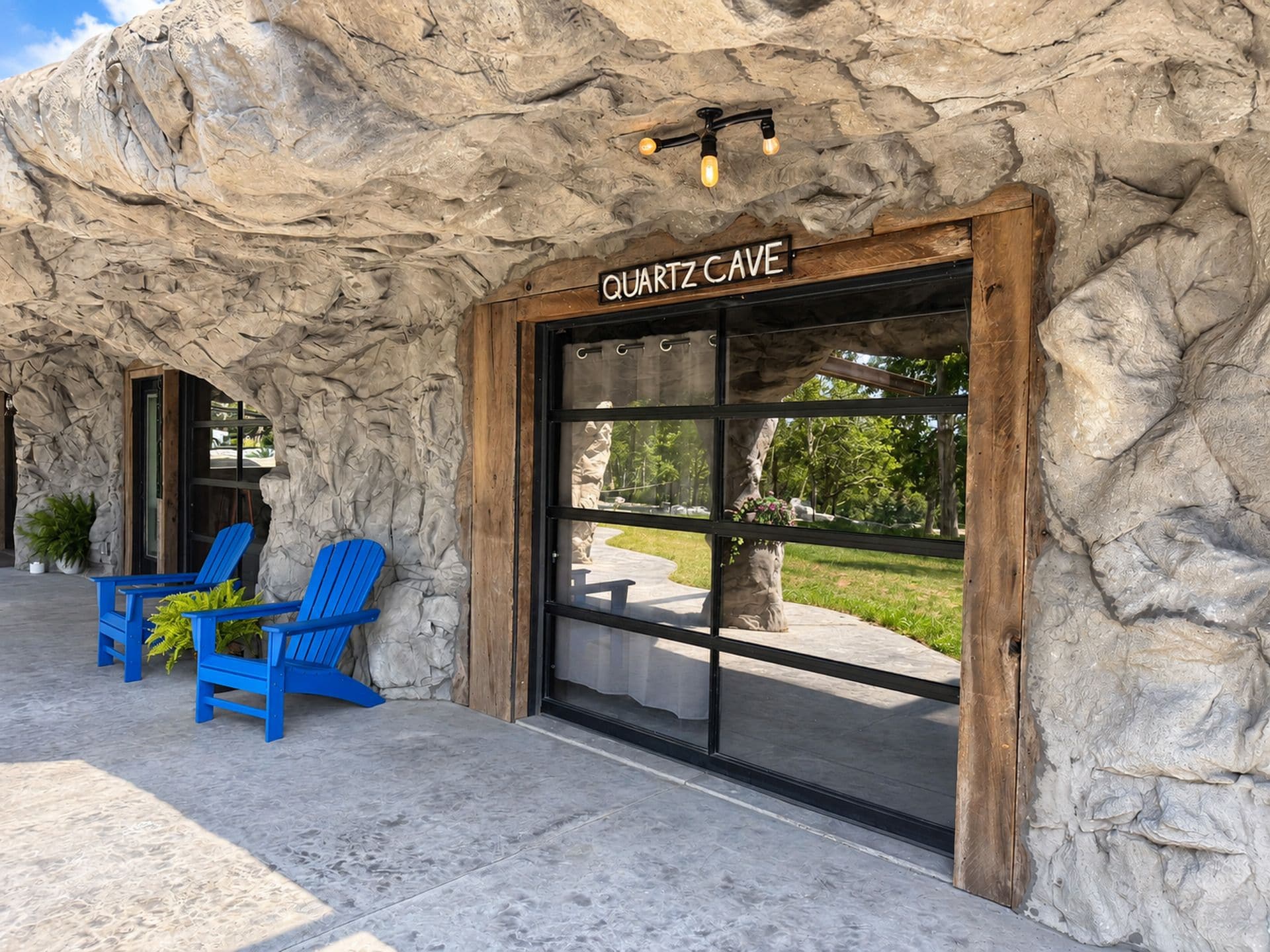 A building with a sign reading 'QUARTZ CAVE' and a stone facade. There are two blue chairs outside.