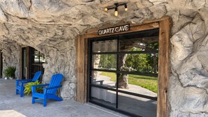 Um edifício com uma placa que diz 'QUARTZ CAVE' e fachada de pedra. Duas cadeiras azuis estão do lado de fora.
