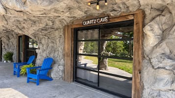 A building with a sign reading 'QUARTZ CAVE' and a stone facade. There are two blue chairs outside.
