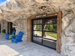 Un edificio con un letrero que dice 'QUARTZ CAVE' y fachada de piedra. Hay dos sillas azules afuera.