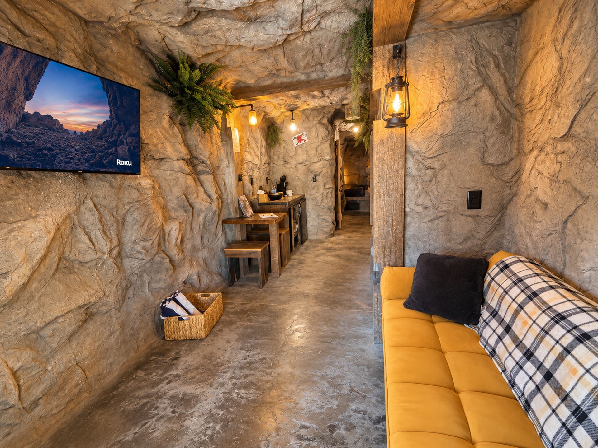 Un intérieur chaleureux avec un mur en pierre, un téléviseur à écran plat, un canapé et un coin repas.