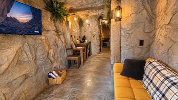 Un intérieur chaleureux avec un mur en pierre, un téléviseur à écran plat, un canapé et un coin repas.