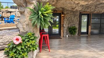A stone facade with a door, a red stool, and a potted plant.