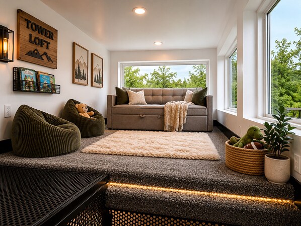 A modern living room with a sofa, a rug, and a bench. There are books on a shelf and a sign on the wall.