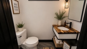 Un bagno piccolo con il water, un lavandino e una finestra sopra il lavandino.