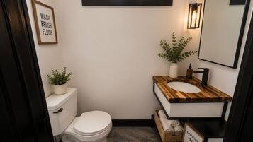 A compact bathroom with a toilet, sink, and a window above the sink.