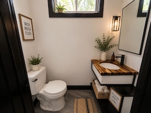 A compact bathroom with a toilet, sink, and a window above the sink. - Altura Tower - With a View (Lancaster)