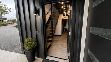 A modern building entrance with a staircase leading inside, a potted plant, and a doormat.