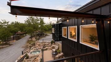 A deck with a hot tub, outdoor seating, and a view of a building with large windows.