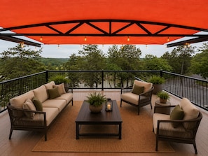 A deck with a sofa set, chairs, a coffee table, and potted plants.